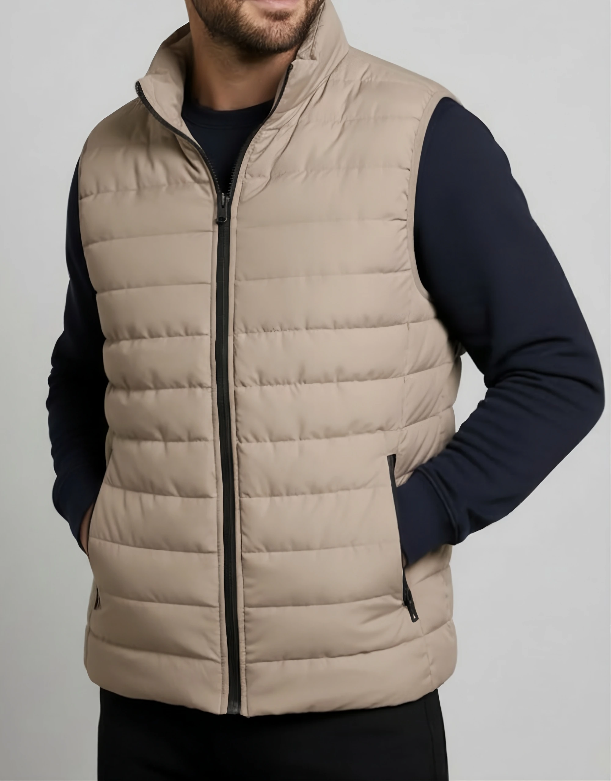 Men's beige quilted puffer vest worn on model showing horizontal baffle channels black contrast zipper and zippered side pocket