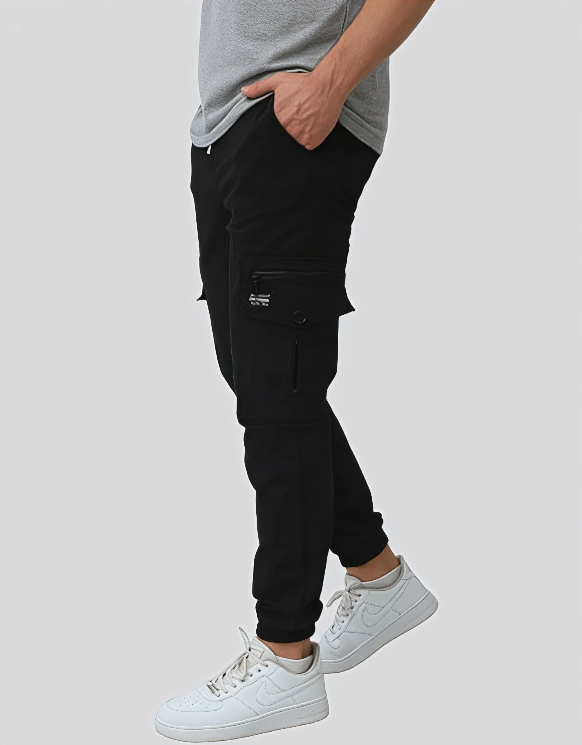 Men's black cargo jogger pants worn on model left side view showing white contrast zipper hardware brand label patch and elasticated ankle cuff