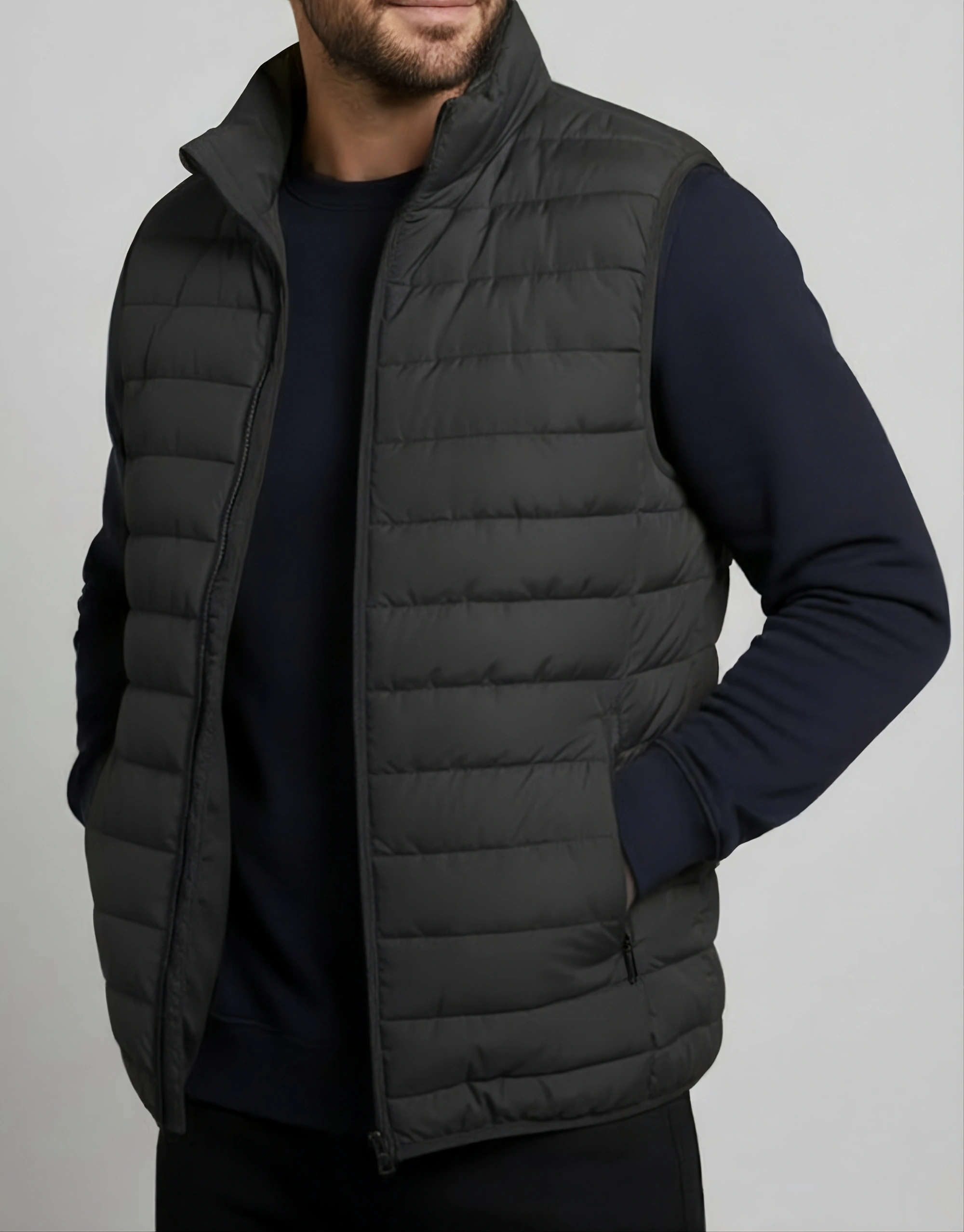 Men's black quilted puffer vest worn open on model showing horizontal baffle channels high stand-up collar and zippered side pocket