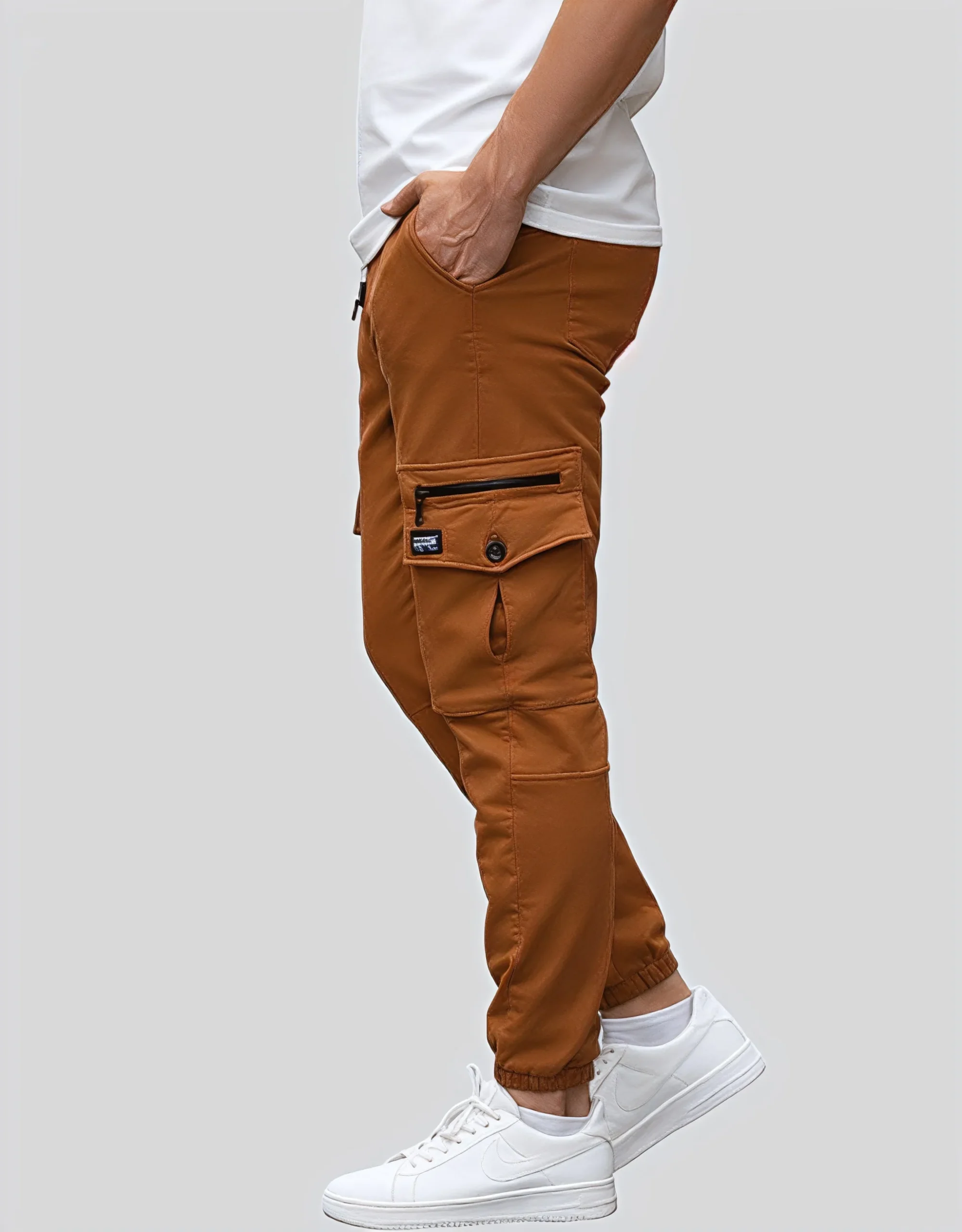 Men's camel cargo jogger pants worn on model left side view showing cargo pocket hardware and slim tapered fit