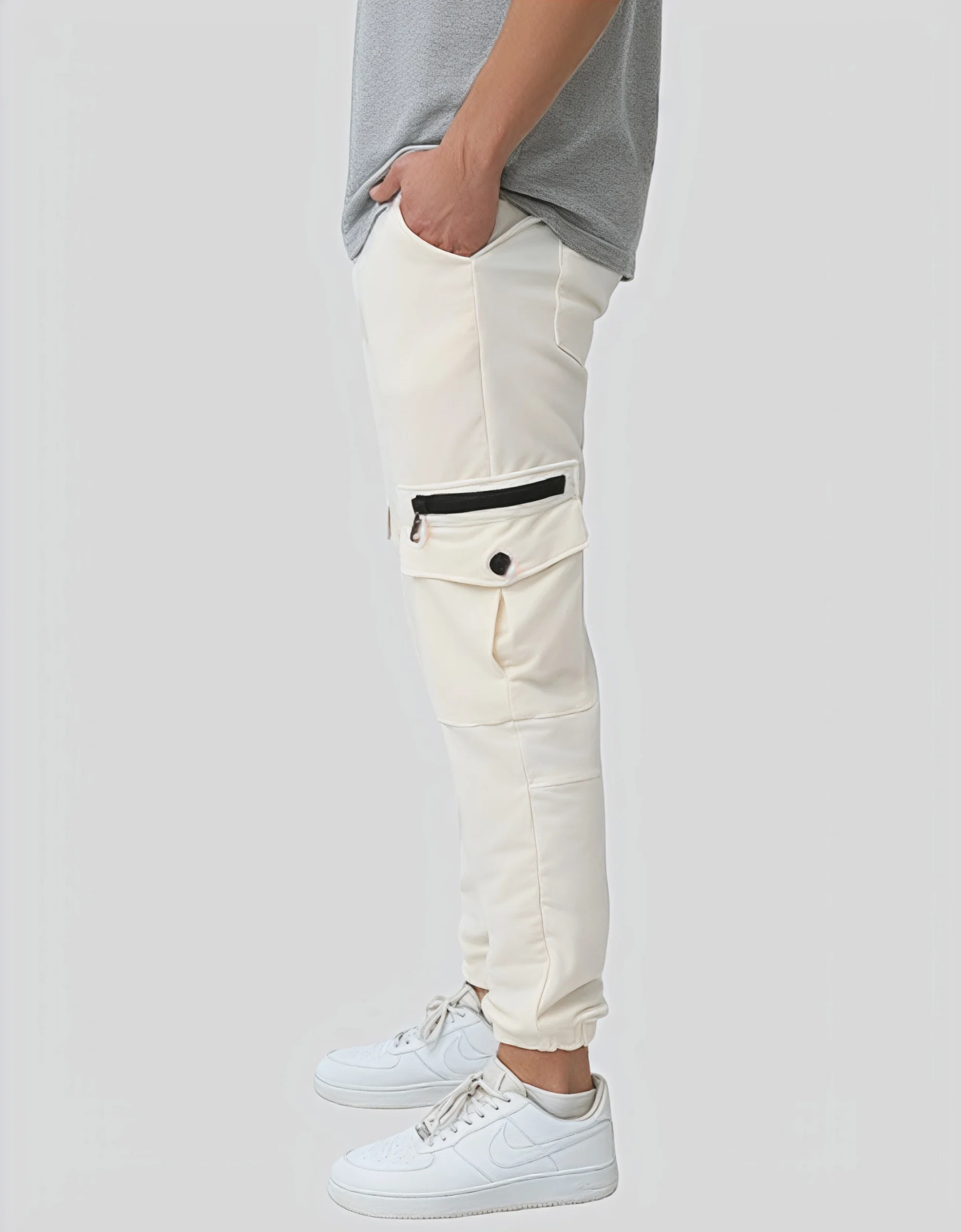 Men's écru cargo jogger pants worn on model left side view showing cargo pocket hardware and elasticated ankle cuff